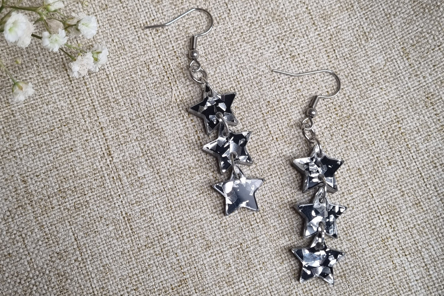Musta-hopea glitter flakes Tähdenlento-korvakoru kolmella tähdellä ja korvakorukoukuilla. 